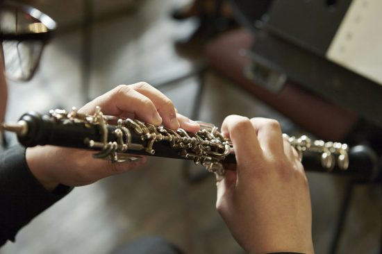A closeup of a person playing the oboe, indoors